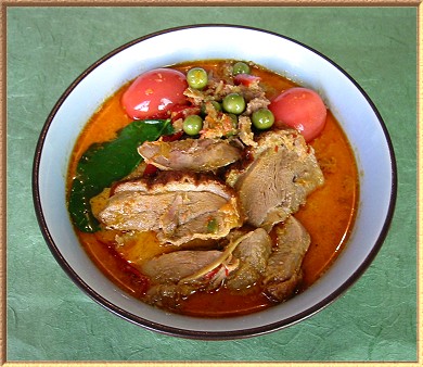 A photo of a deep bowl decprated with Siamese people on the outside and containing sucullent duck curry on the inside.